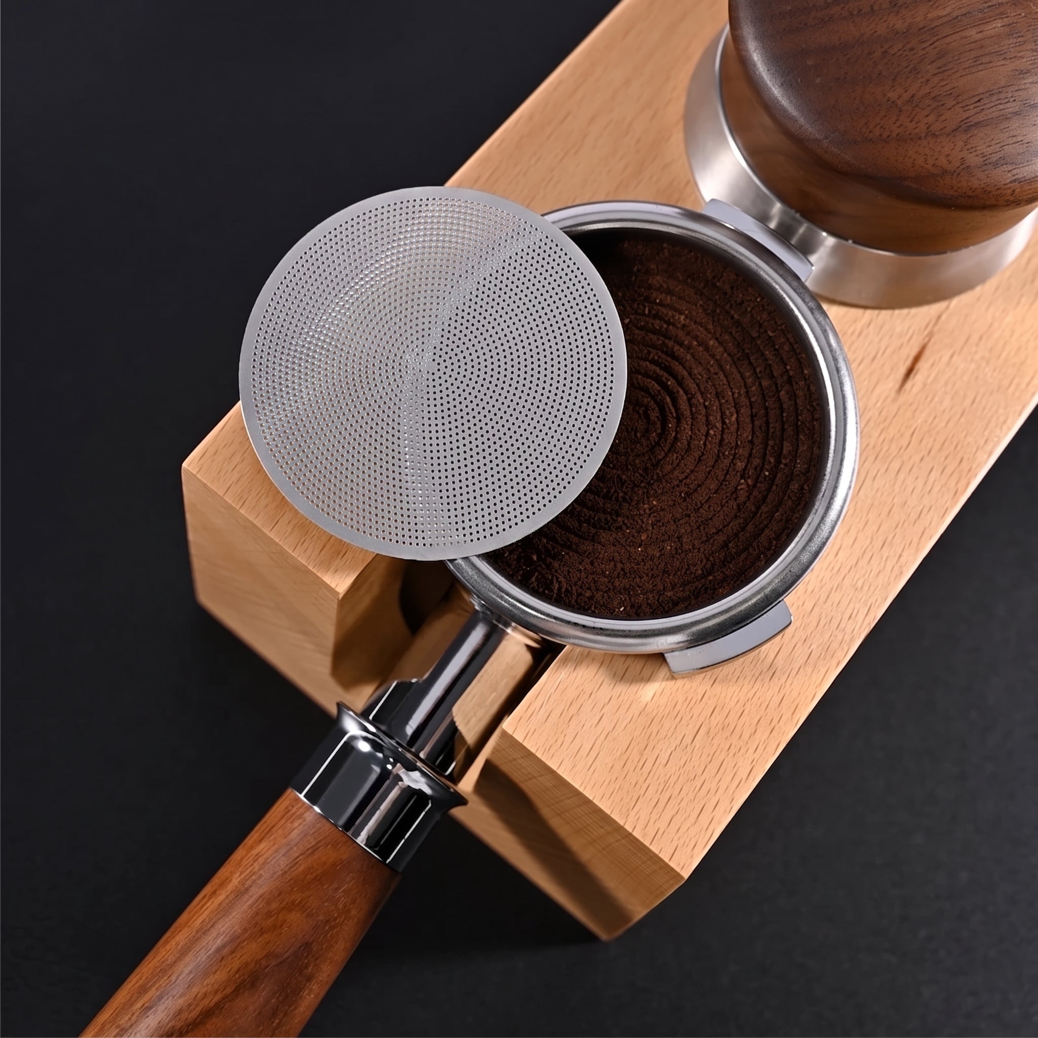 Puck screen resting against a portafilter on a wooden tamping station